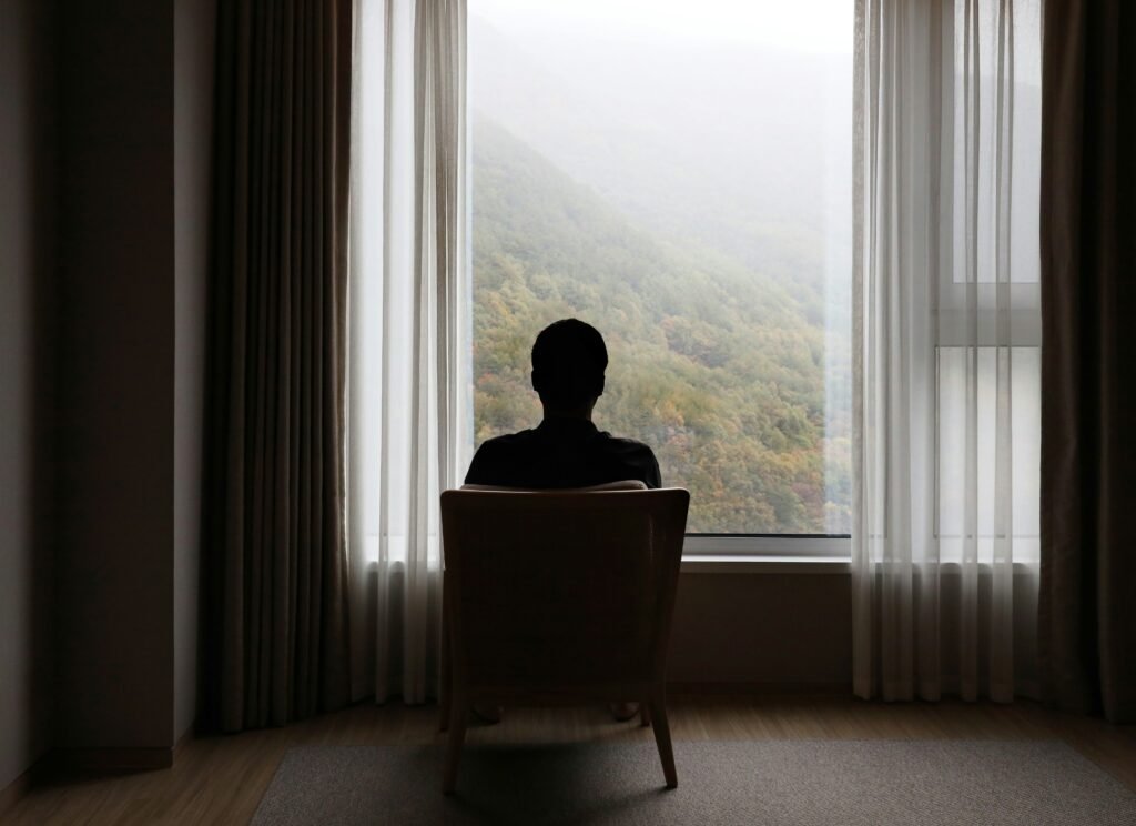 Man looking out window reflecting signs of depression in men
