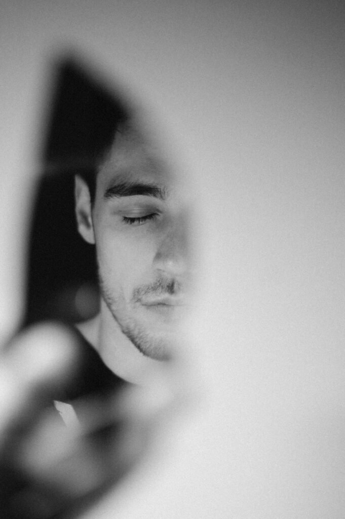 high estrogen in men symptoms - middle-aged man looking concerned in mirror