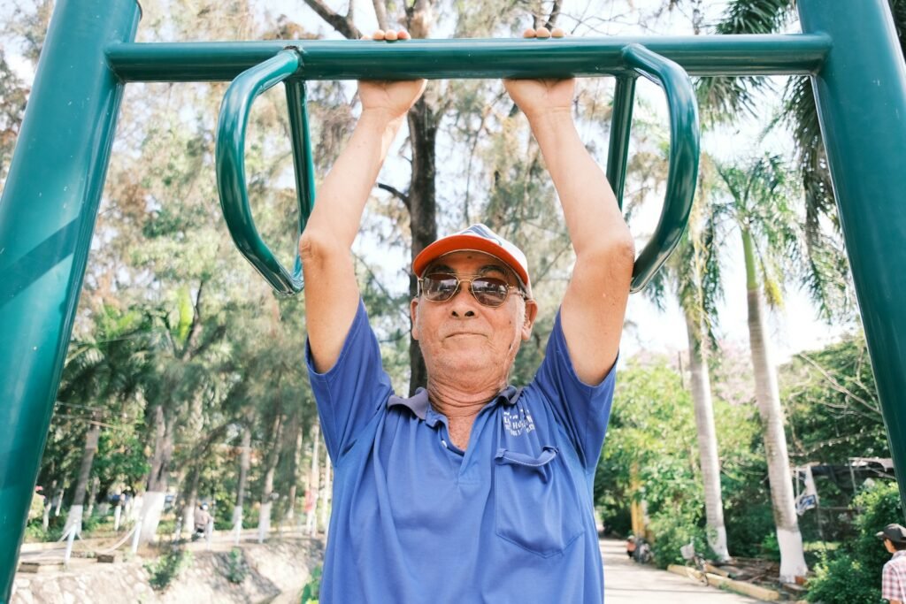 Older man doing pull-ups outdoors, illustrating lifelong strength training for men