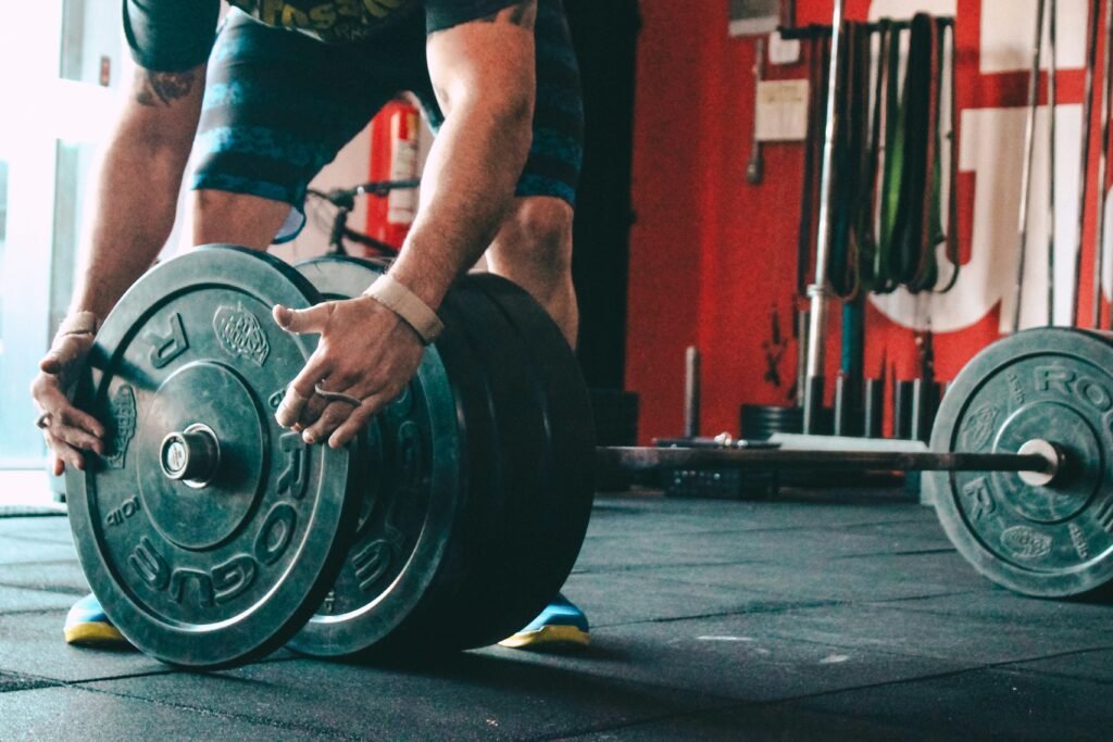 man adding weight plates to a barbell using progressive overload