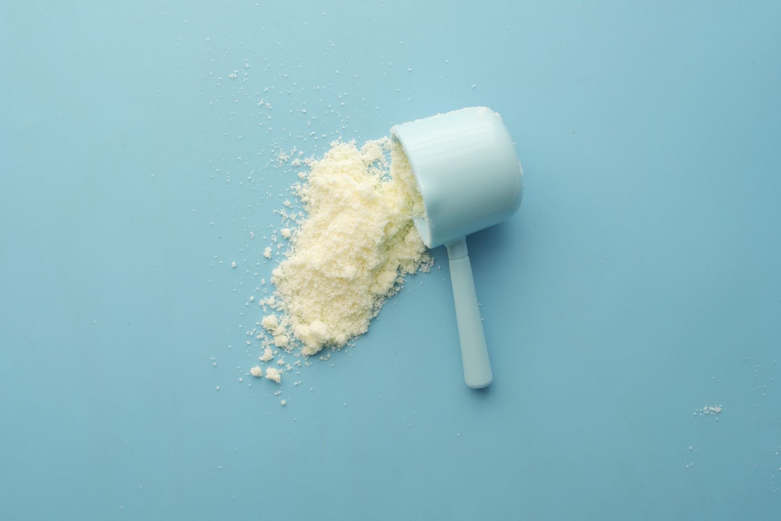 A scoop of white powder spilled on a blue surface