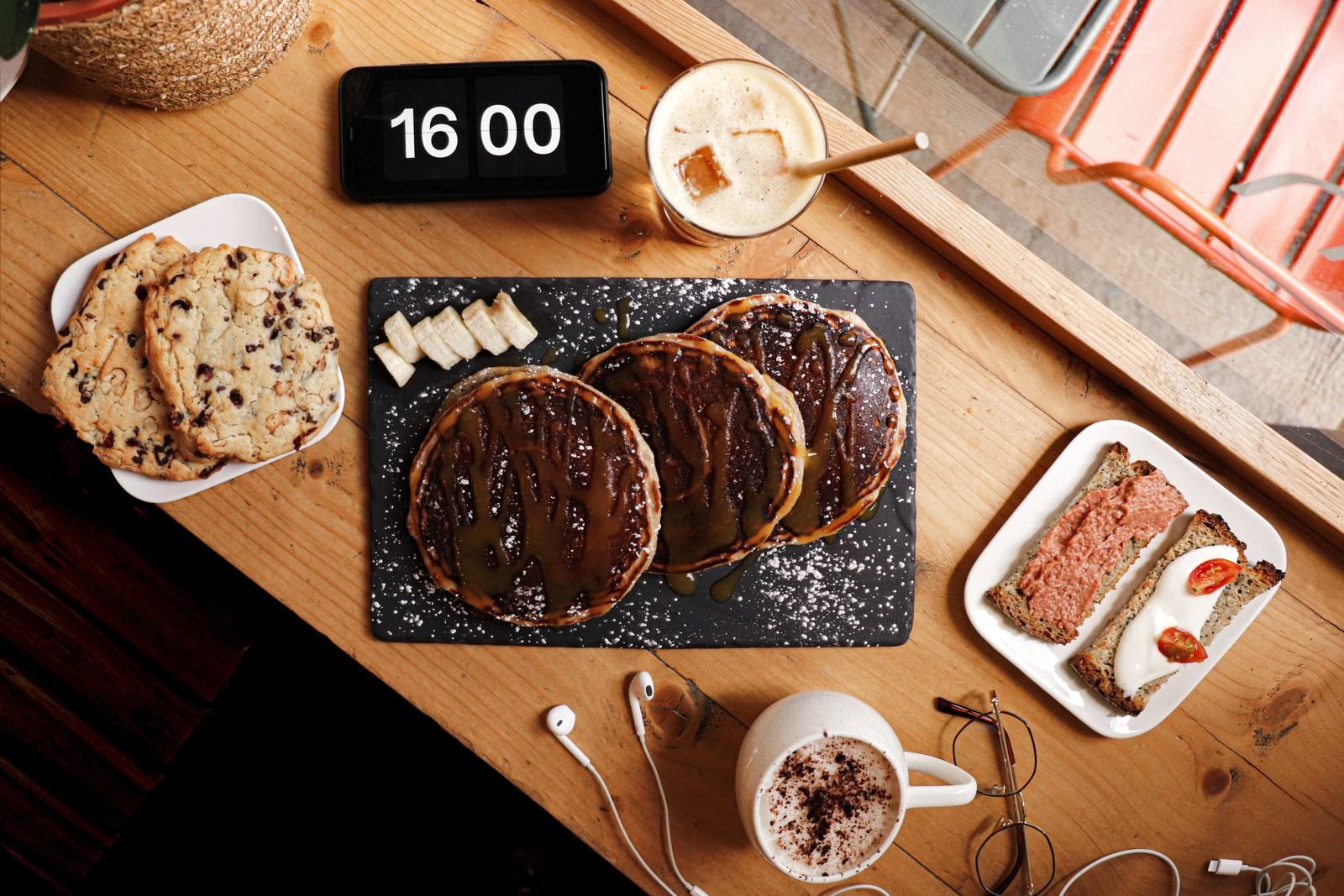 Afternoon table of pancakes, coffee and snacks beside a clock