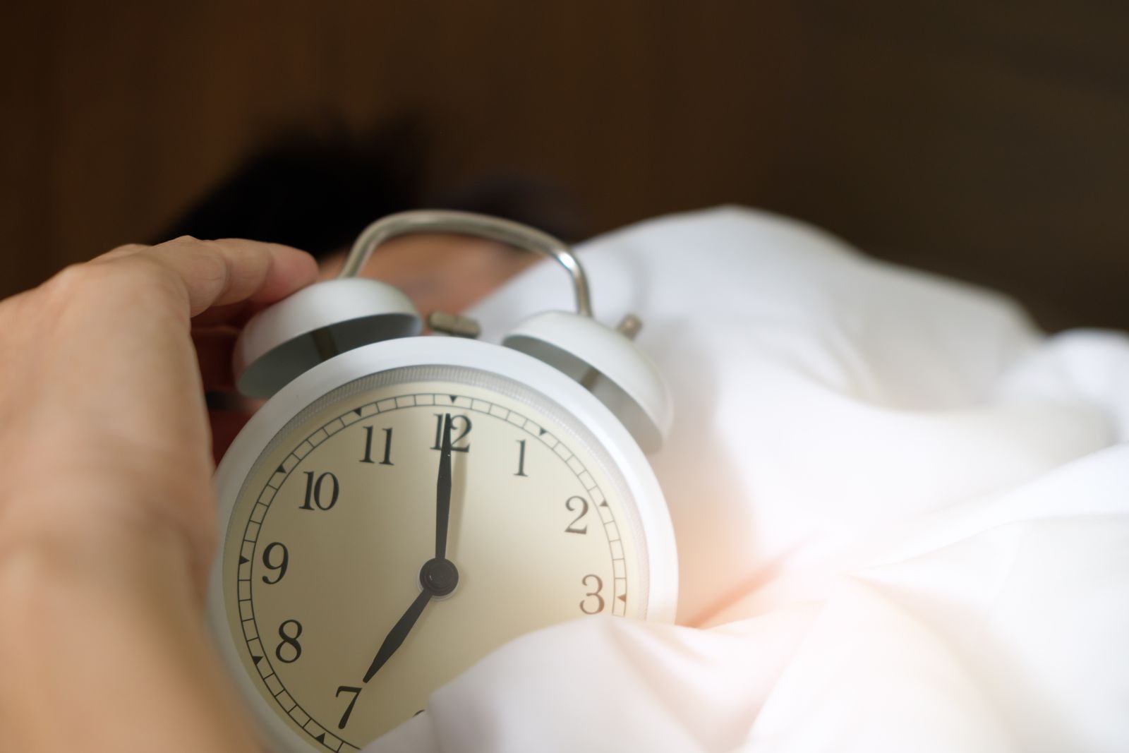 Alarm clock on a bed in the early morning