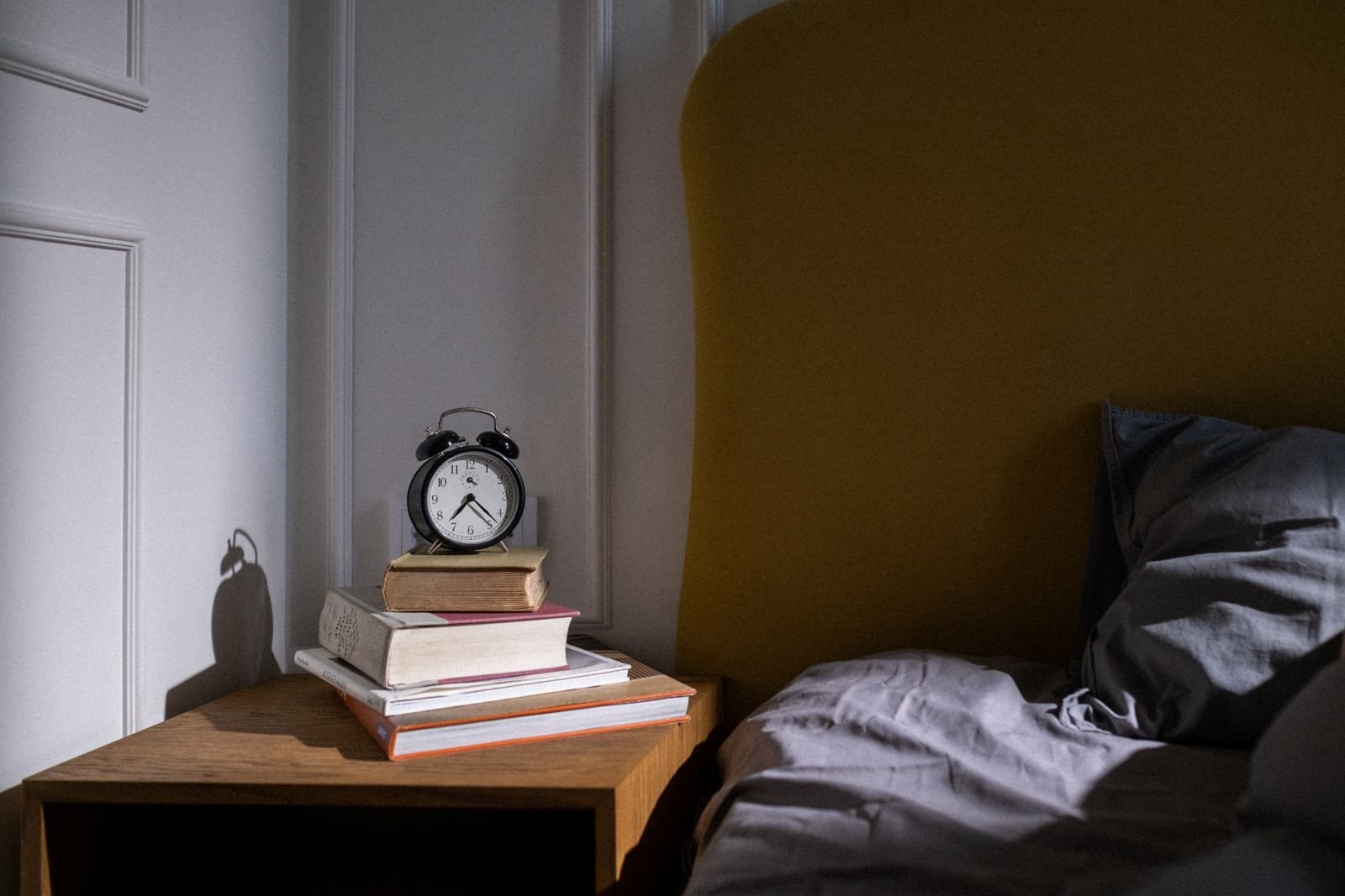 Alarm clock on a stack of books by the bed