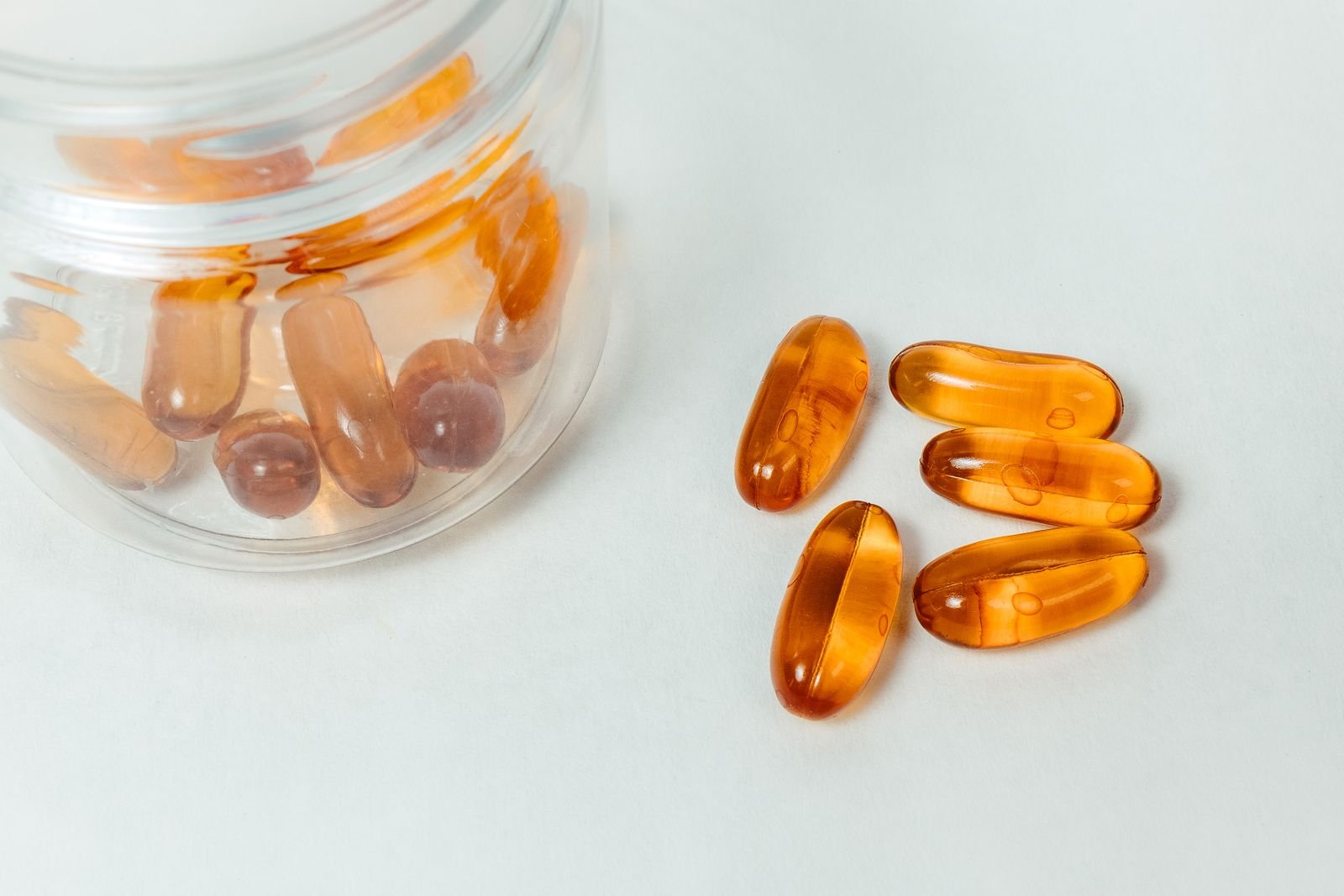 Amber vitamin D softgels spilling from a glass jar