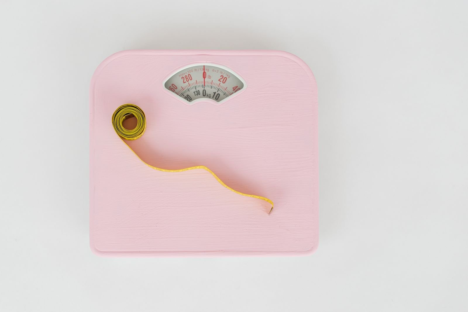 Bathroom scale and a measuring tape on a white background