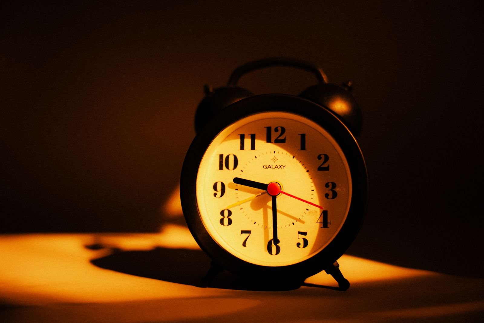Black alarm clock under warm lamplight