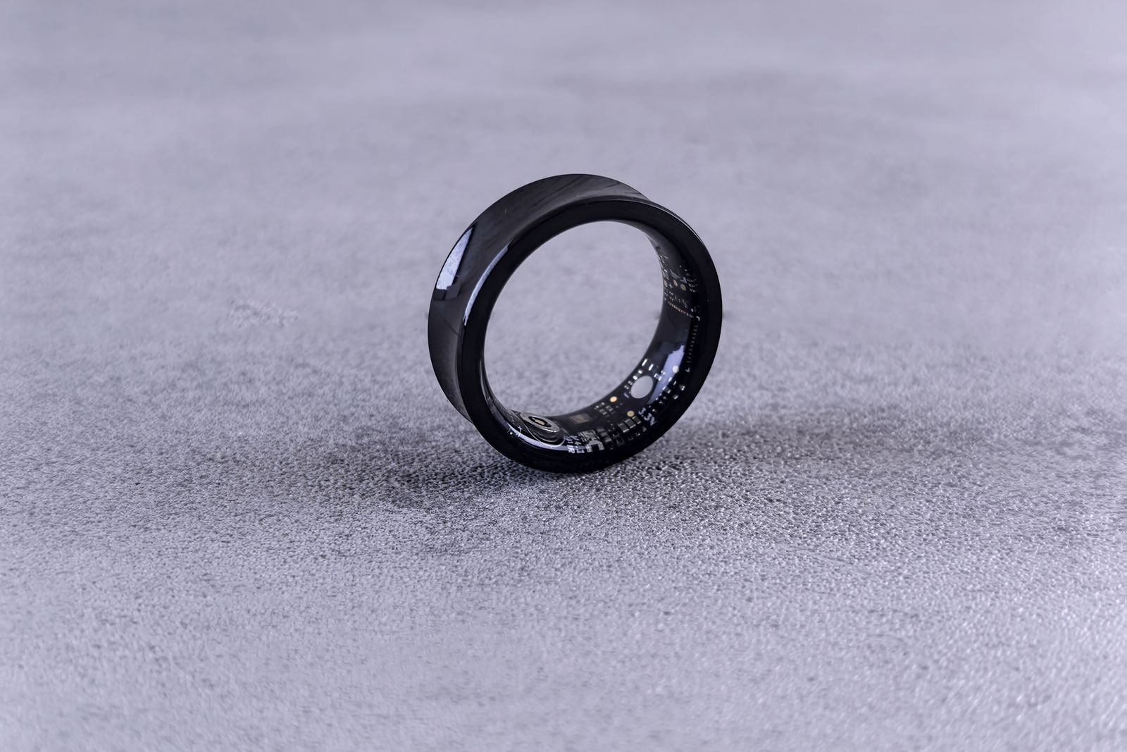 Black smart ring resting on a textured surface