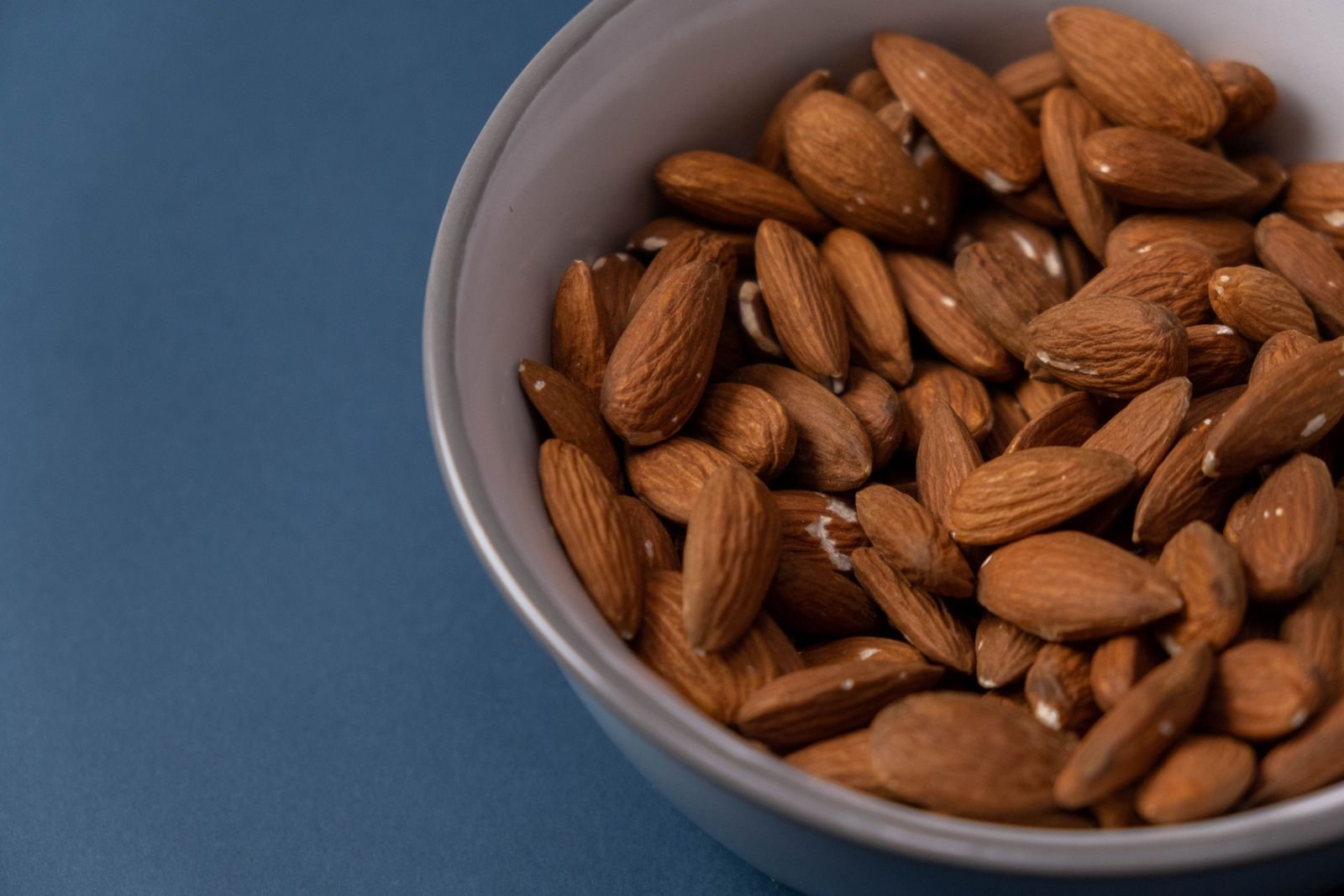 Bowl of almonds on a blue background