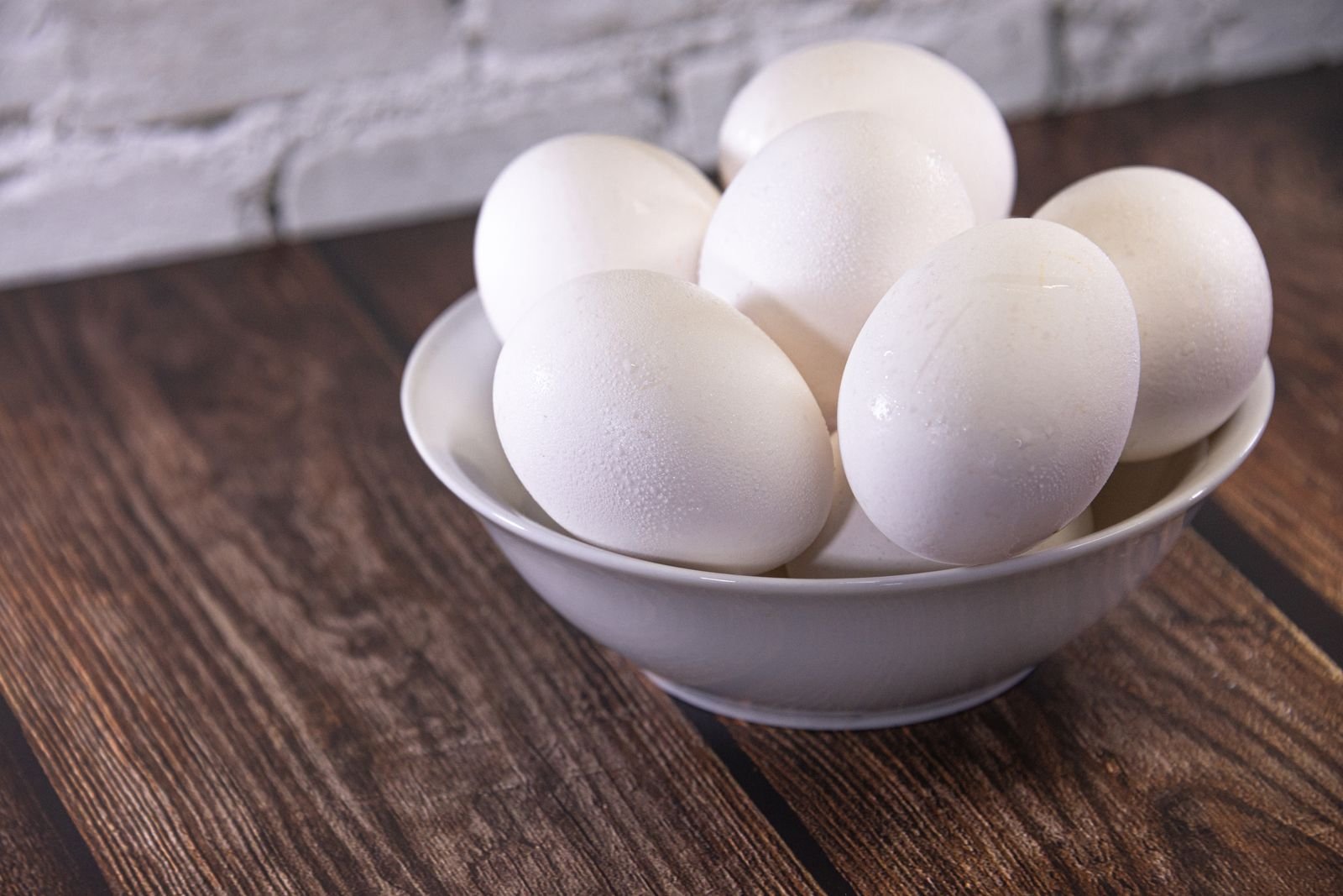 Bowl of white eggs on a wooden table