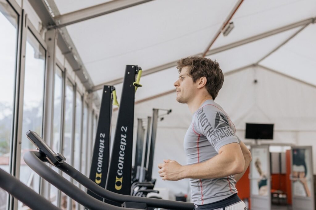 Man running on a treadmill in a gym, representing cardio vs weights for fat loss