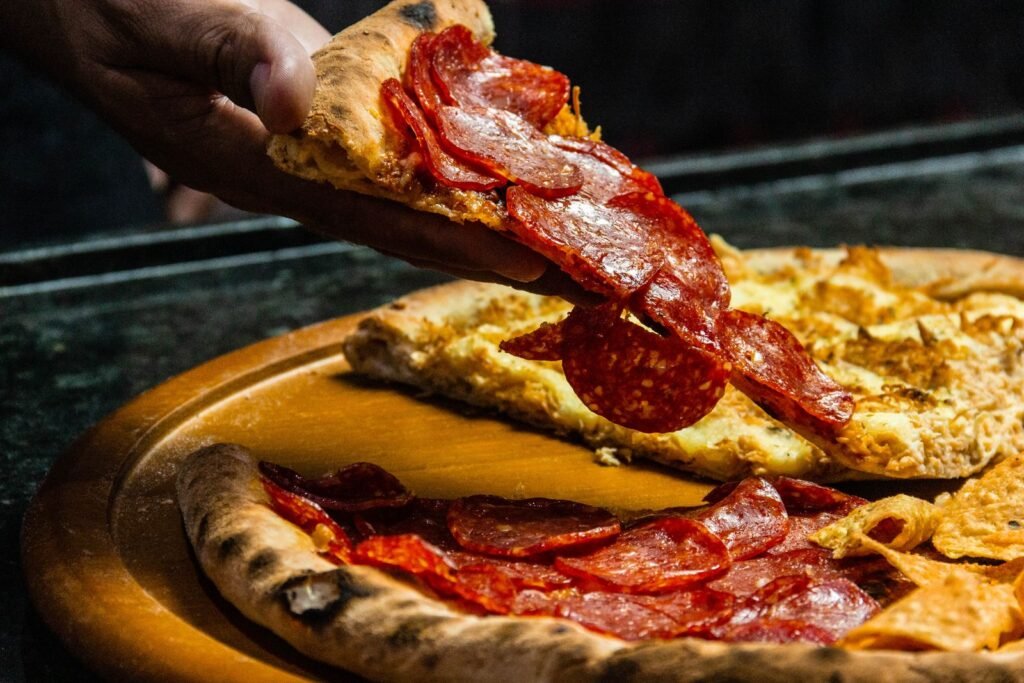 Hand lifting a slice of pepperoni pizza