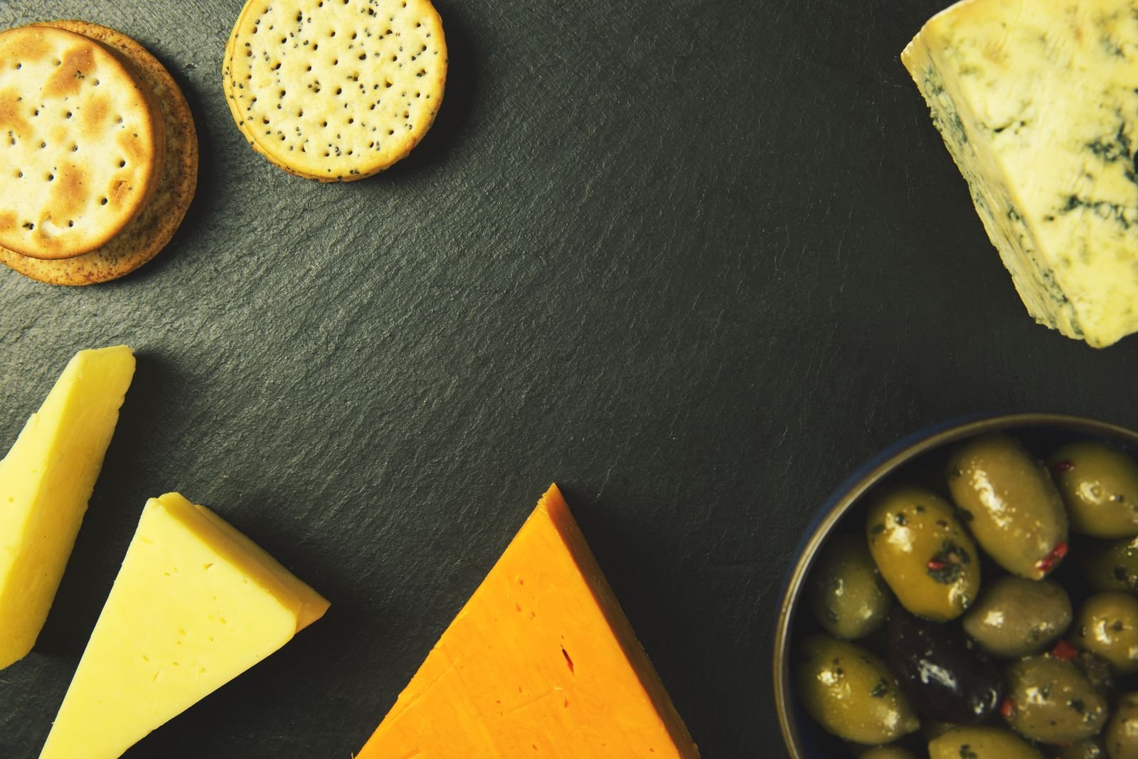 Cheese platter with crackers and olives on slate