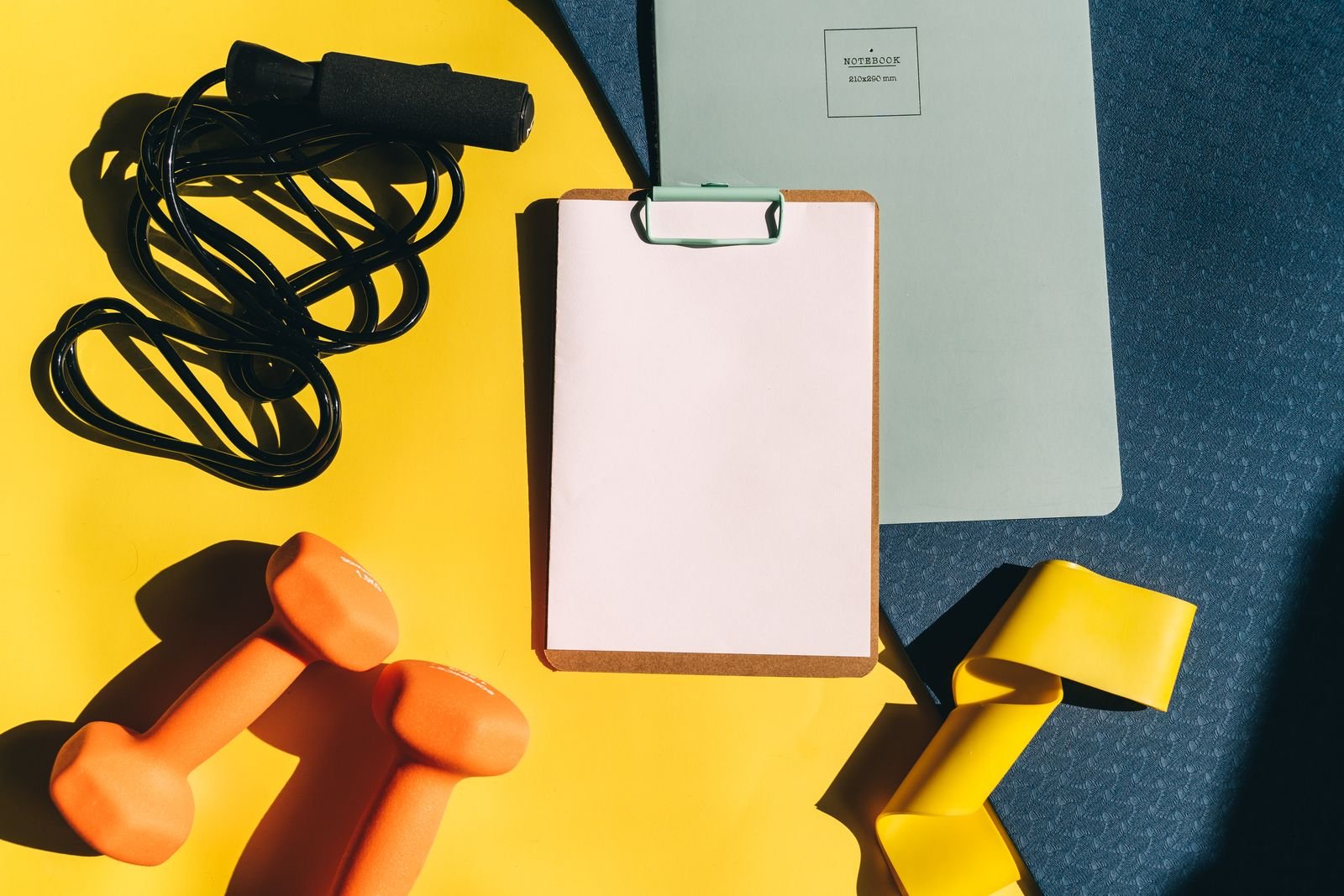 Clipboard, dumbbells and a jump rope laid out for a workout plan