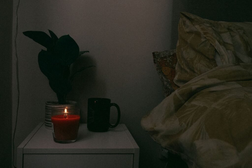 Dark bedroom at night with a candle and a plant