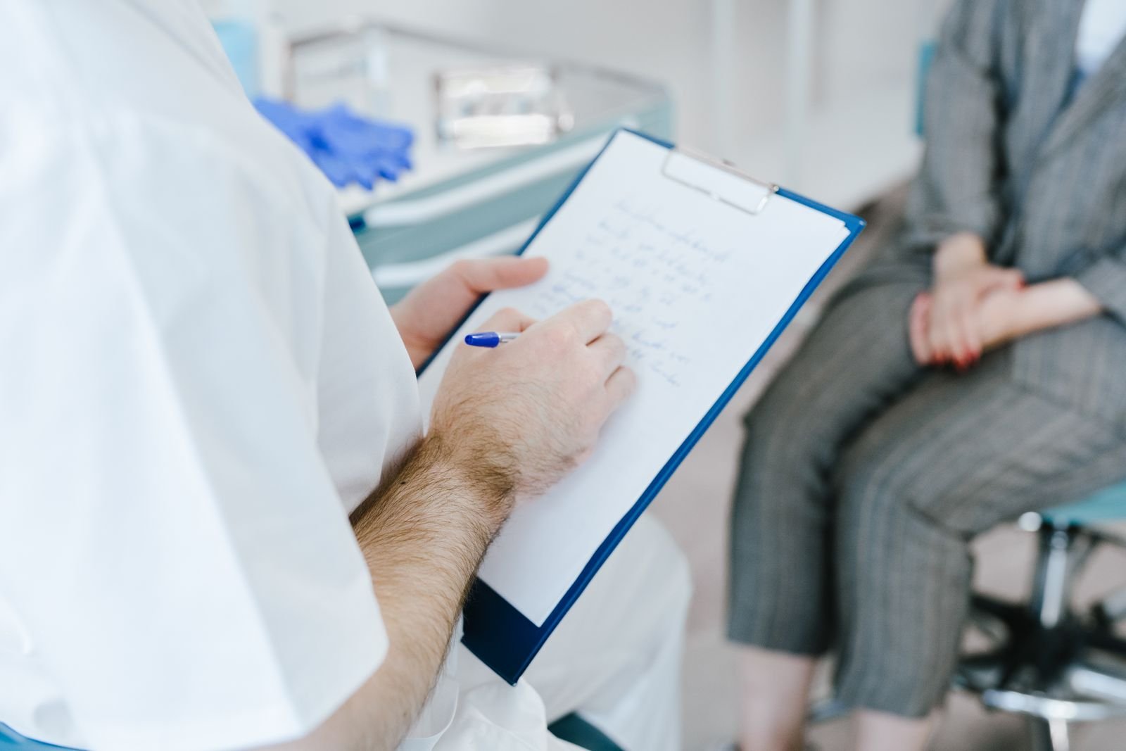 Doctor writing notes on a clipboard during a consultation