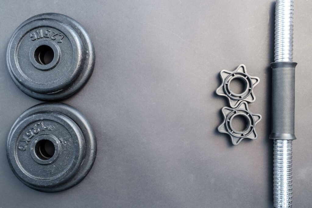 Barbell and two dumbbells arranged on a neutral surface
