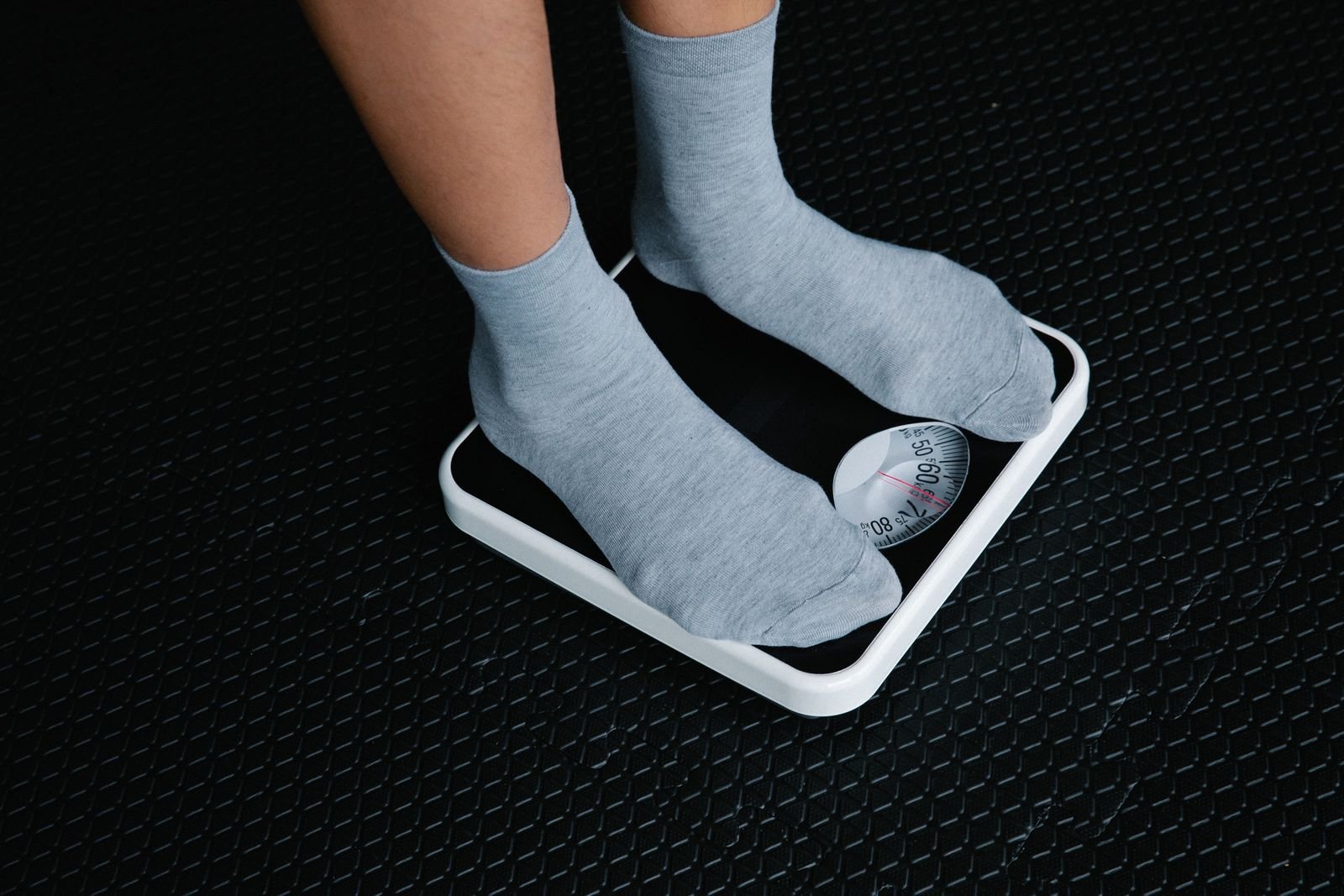 Feet in grey socks standing on a white bathroom scale