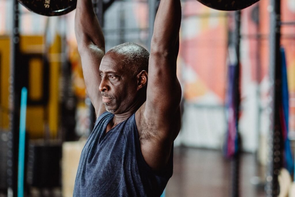Older man training with a barbell in a bright gym