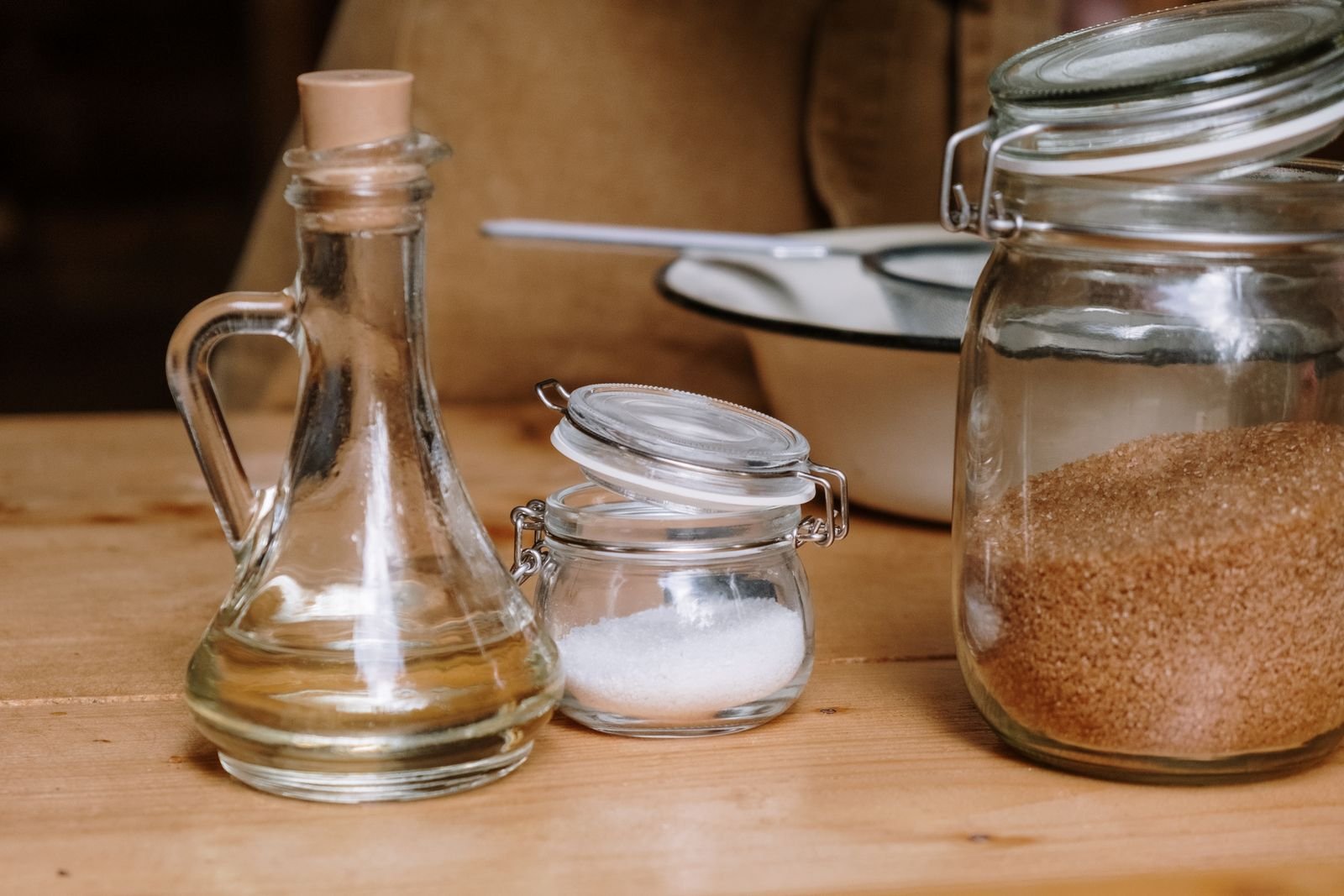 Glass cruet of cooking oil beside jars of kitchen staples
