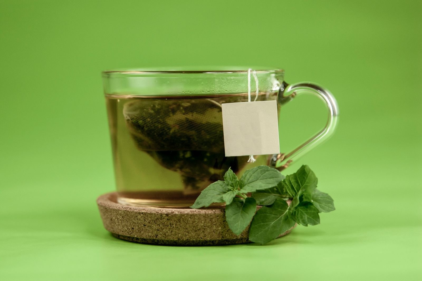 Glass cup of green tea with a tea bag and fresh mint