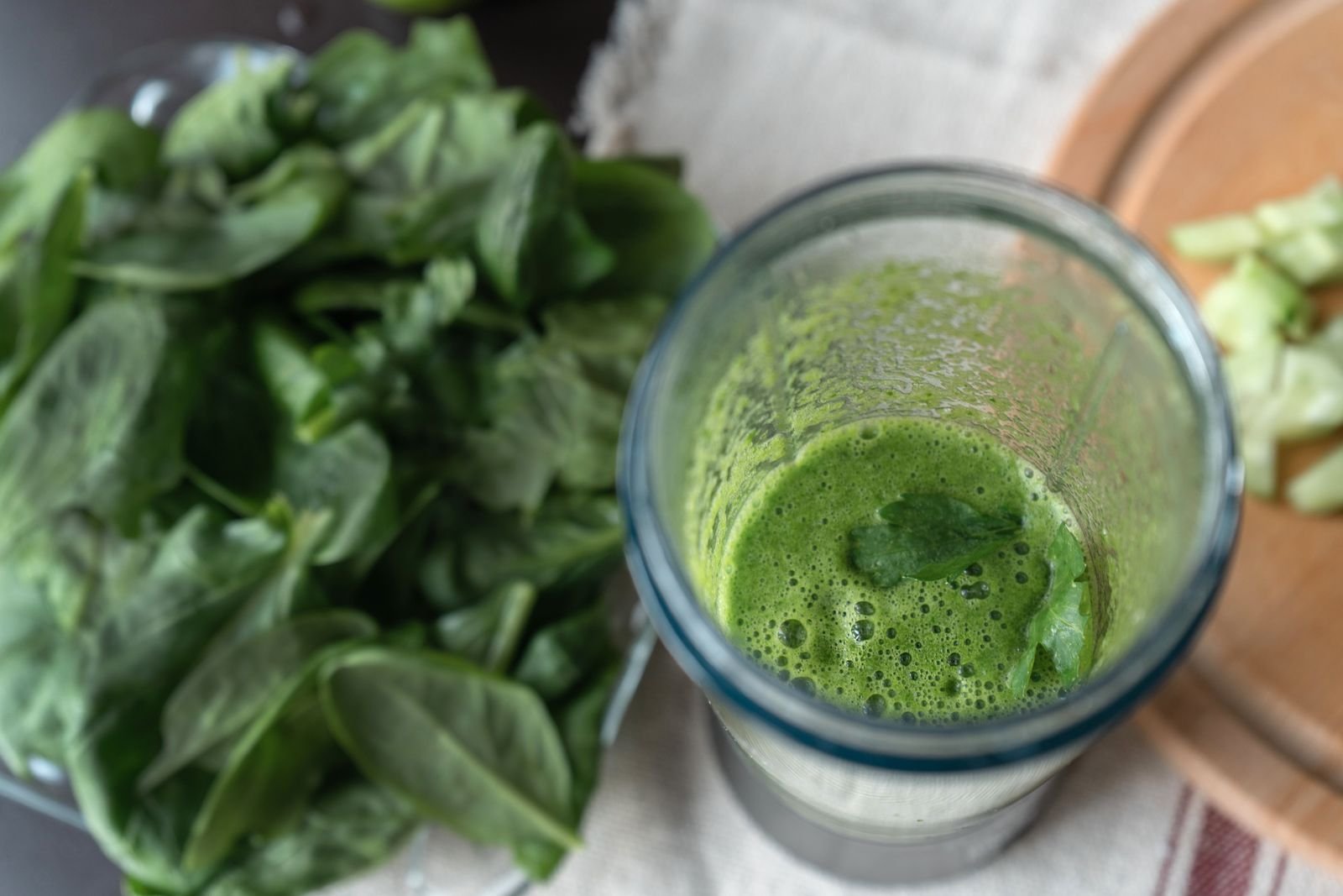 Green smoothie made with spinach and cucumber on a wooden board