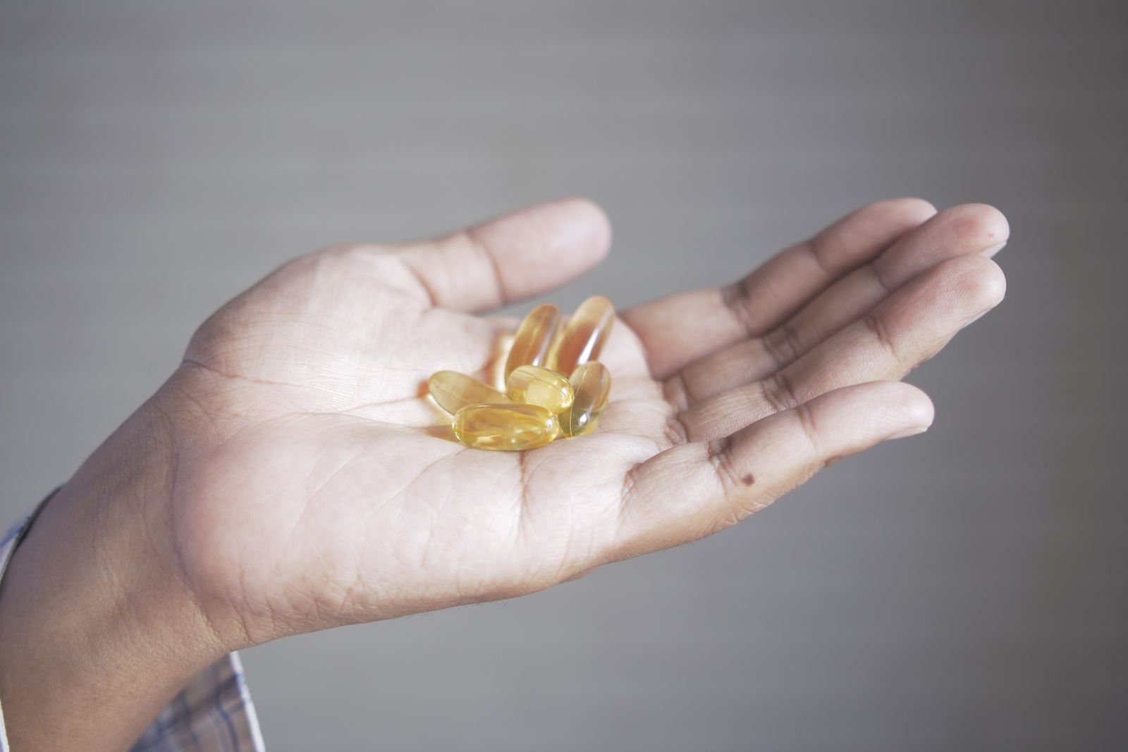 Hand holding a few yellow supplement capsules