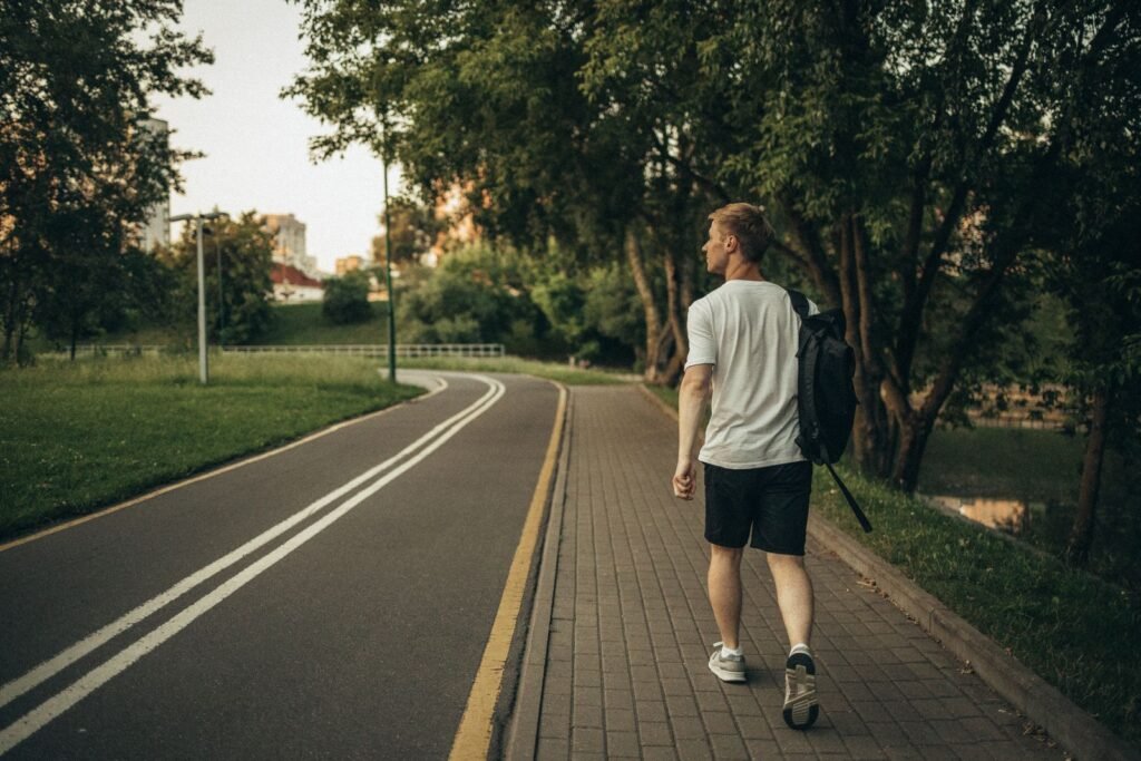 Man walking along a paved park path, illustrating how many steps a day men need