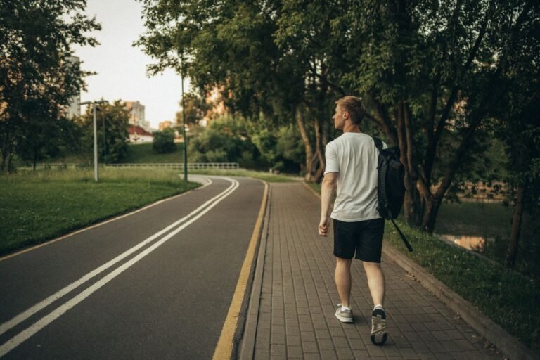 Man walking along a paved park path, illustrating how many steps a day men need
