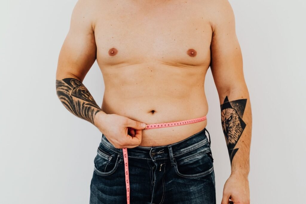 Man measuring his waist with a tape measure to track how much weight he can lose in a month