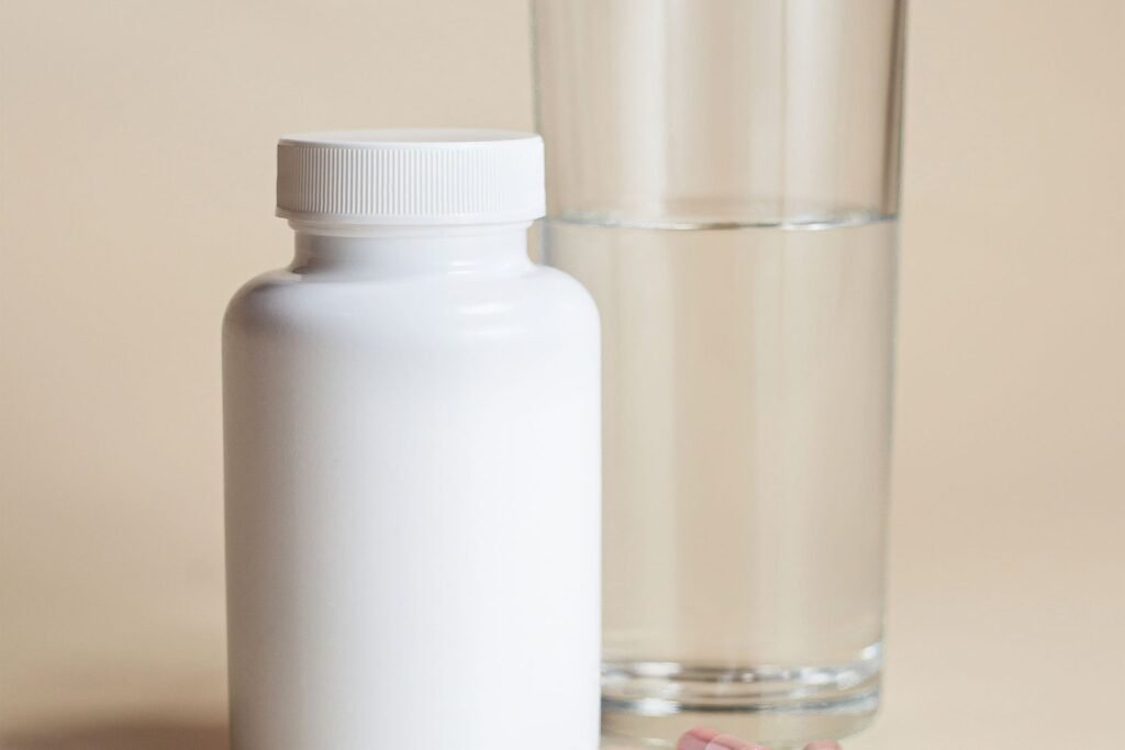 Supplement bottle with capsules and a glass of water