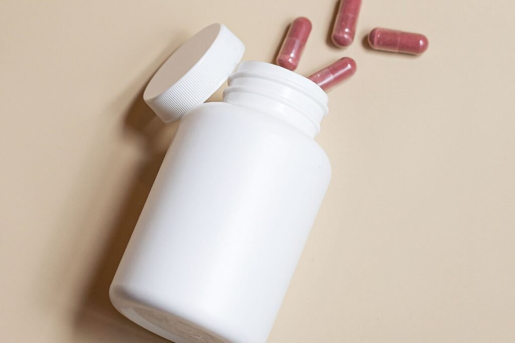 Supplement bottle with its lid open and capsules beside it