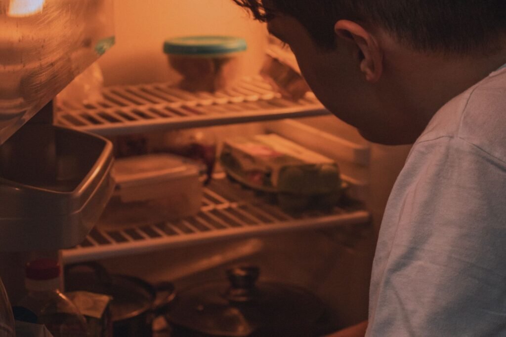 Man looking into a refrigerator lit by its interior light