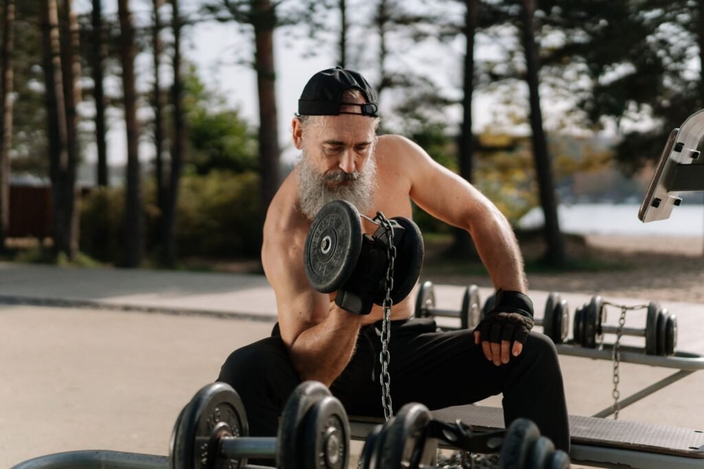 Older man lifting dumbbells in an outdoor gym