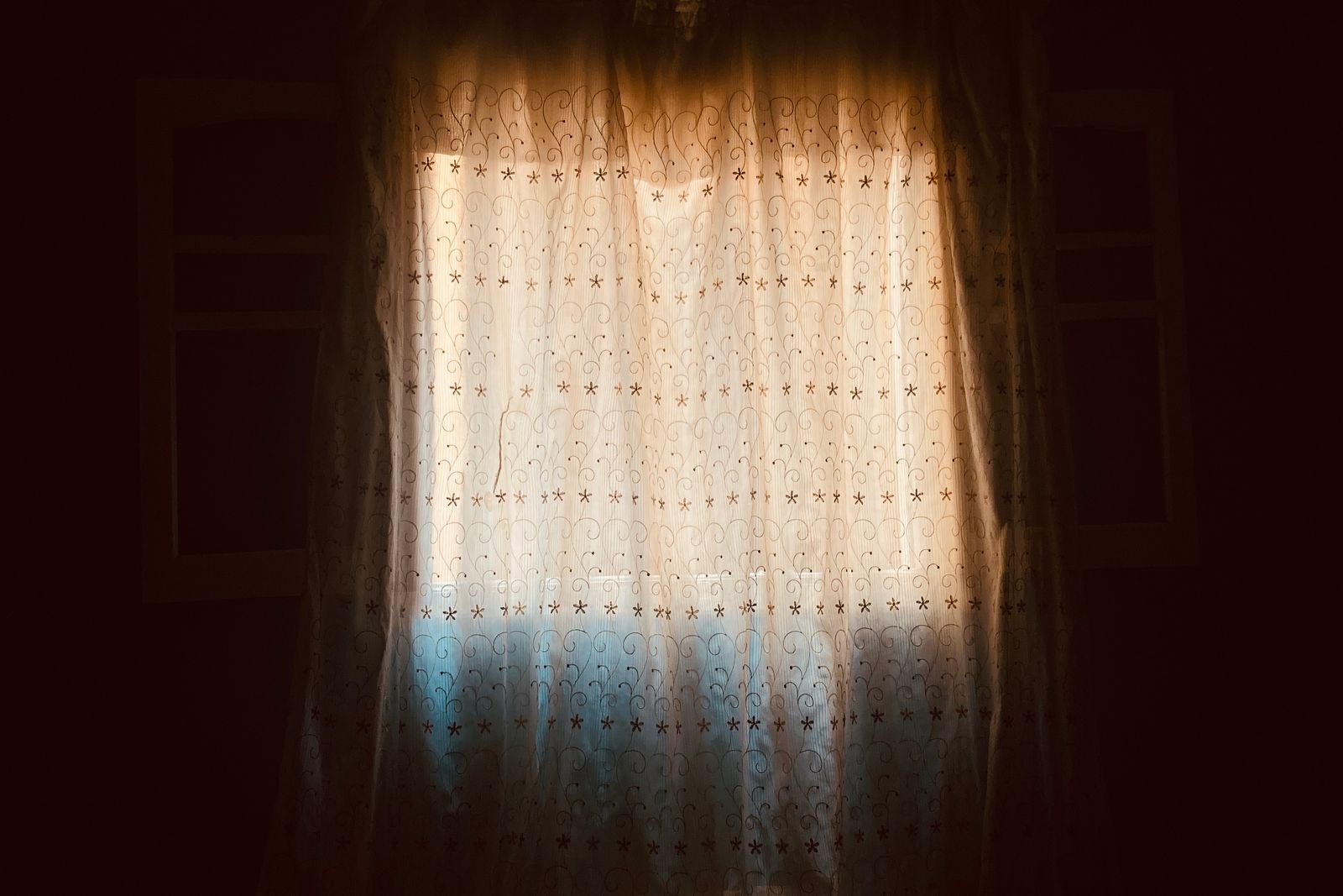 Light glowing through a curtain in a dark room