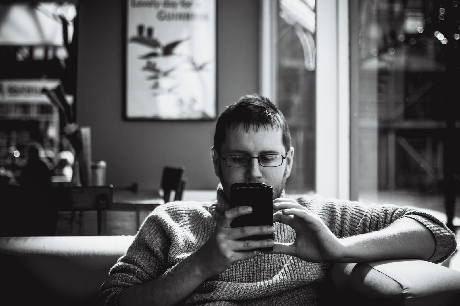 Man absorbed in his smartphone while holding a coffee