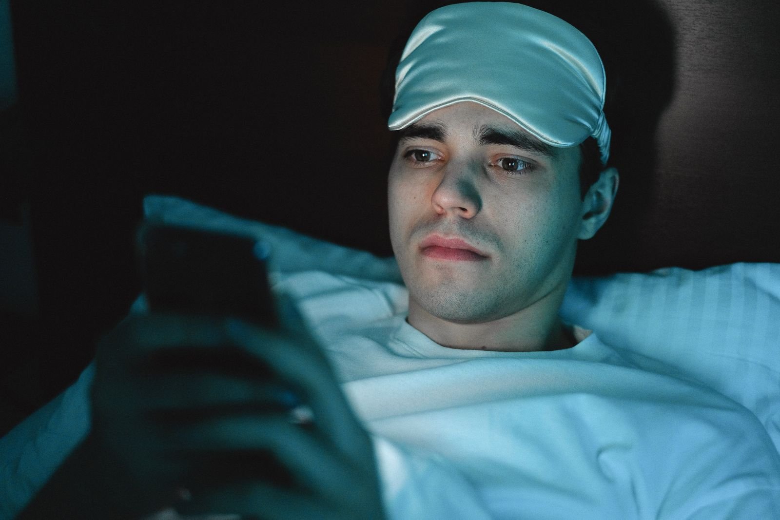 Man awake at night looking at his phone in bed