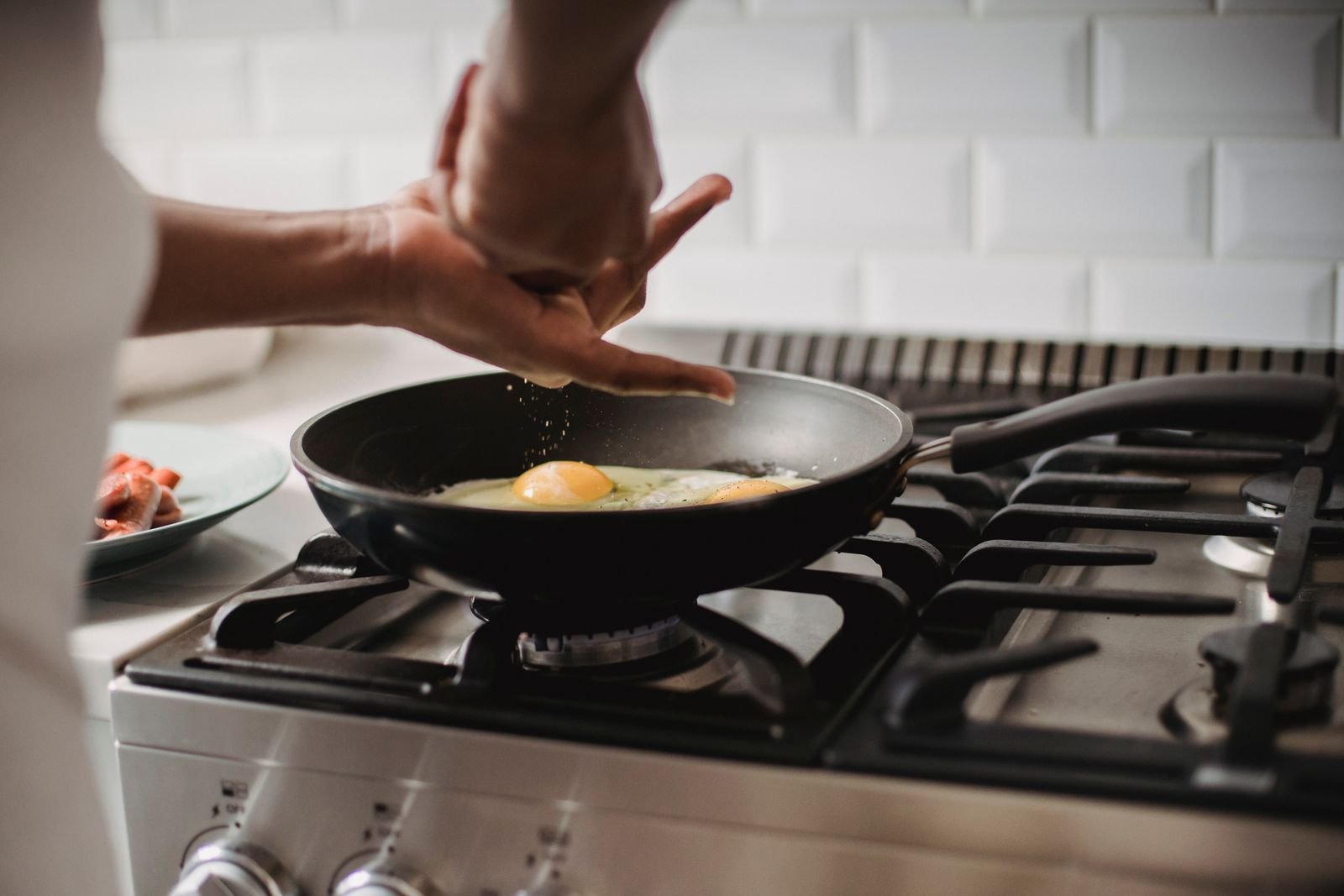 Man cooking eggs in a frying pan on a gas stove