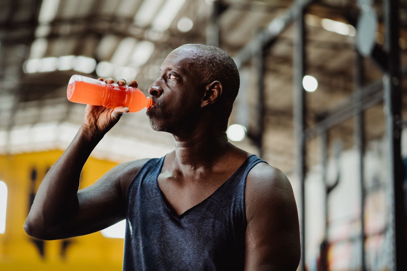 Man drinking from a sports bottle between sets in a gym
