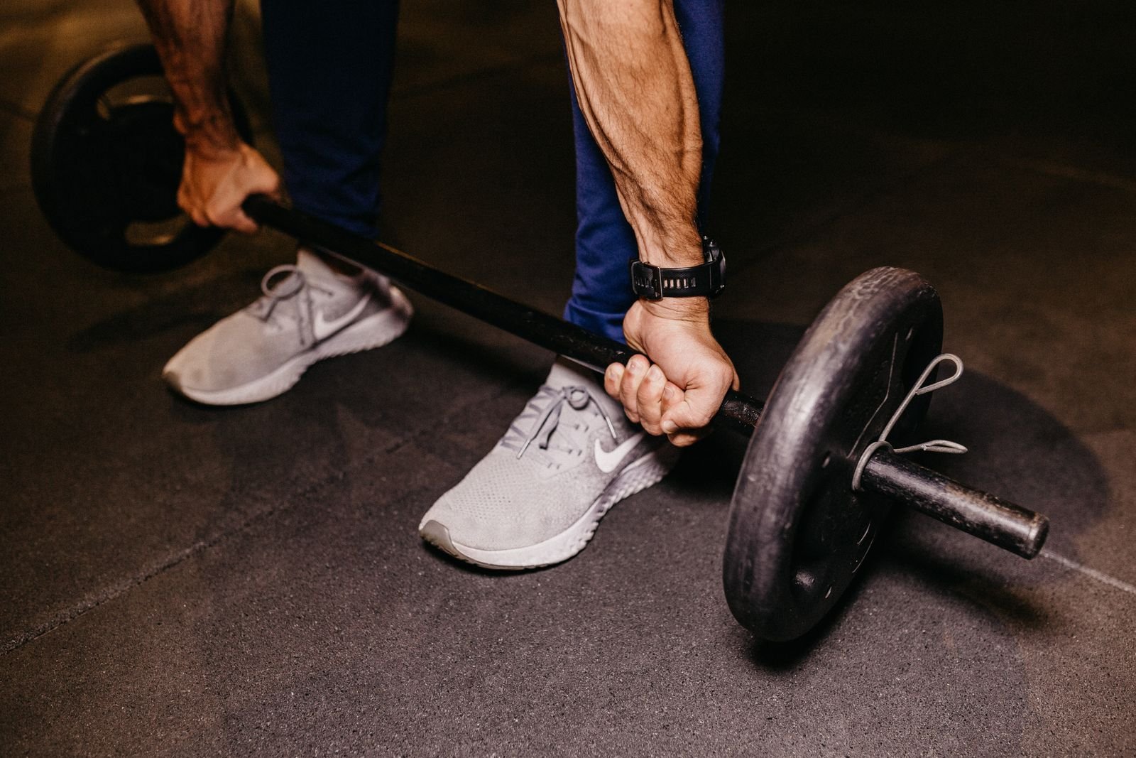 Man gripping a loaded barbell on the gym floor