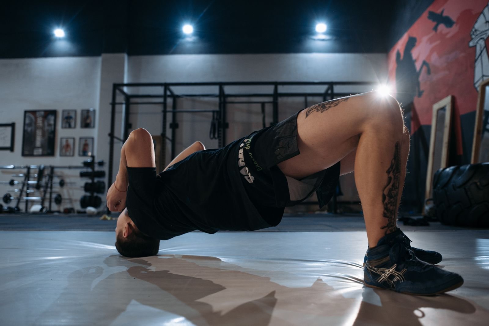 Man holding a floor bridge on a gym mat