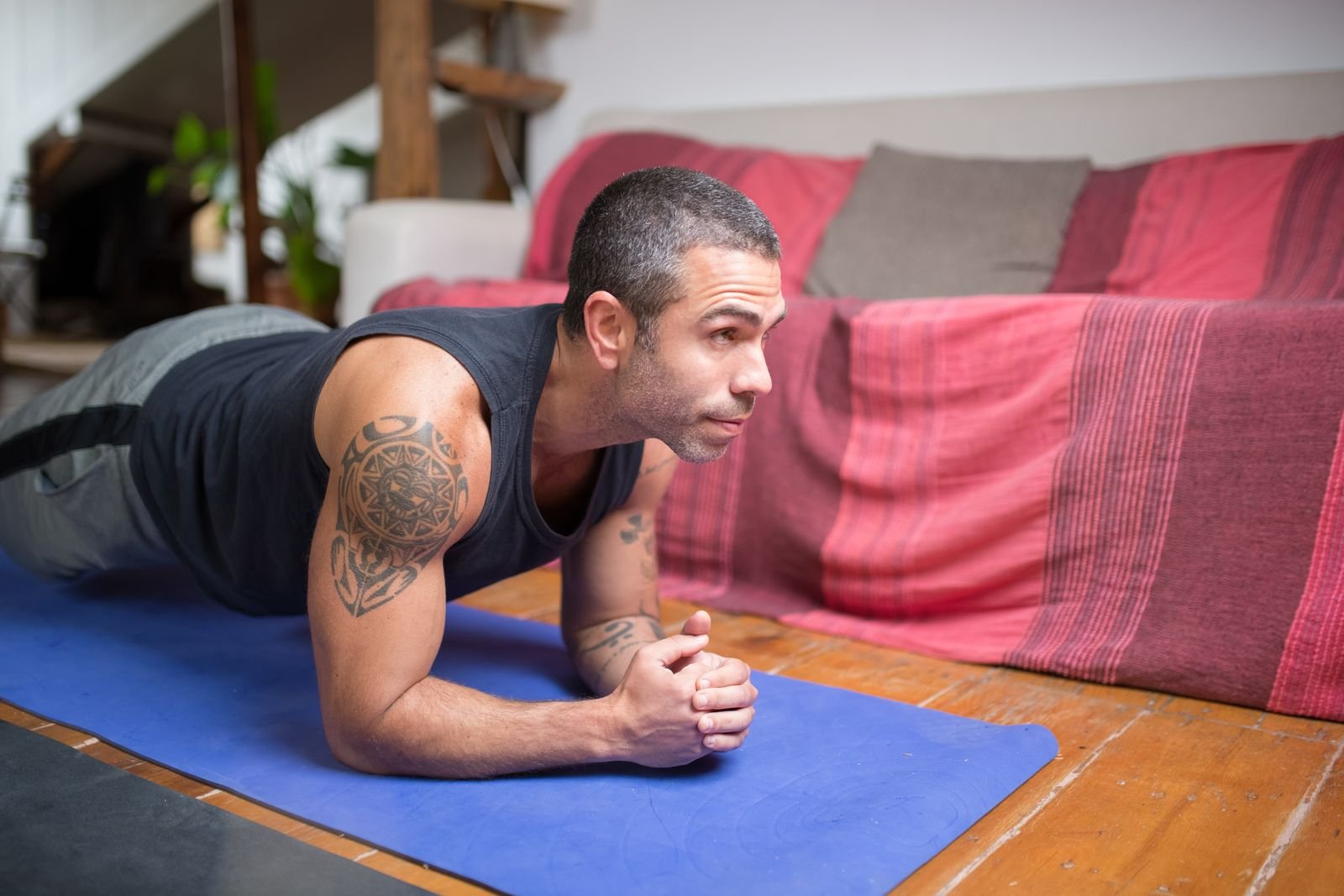 Man holding a forearm plank on a yoga mat at home