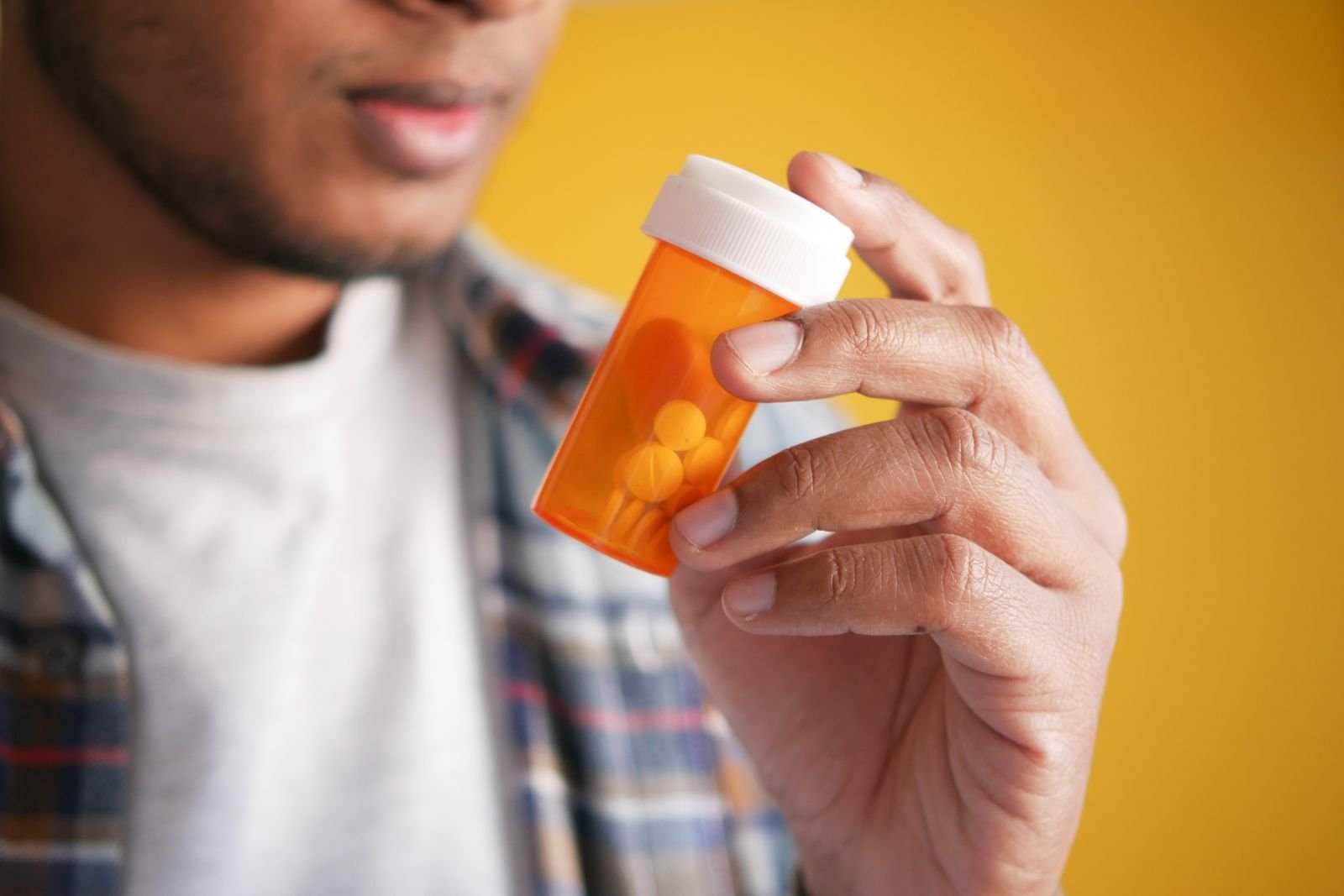 Man holding a pill bottle and reading its label