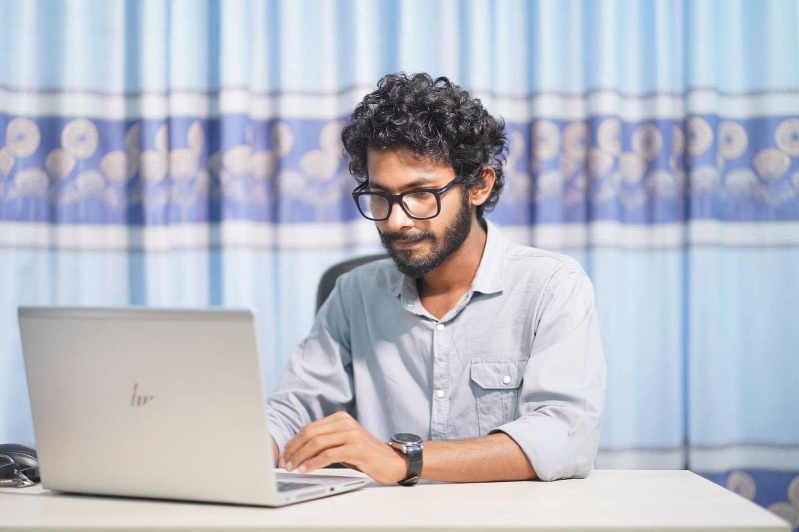Man in glasses concentrating on work at a laptop