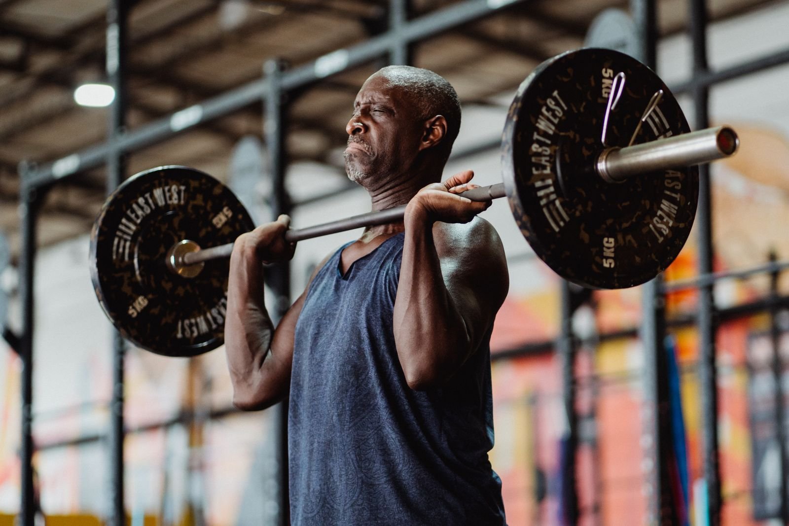 Man pressing a barbell overhead in a gym