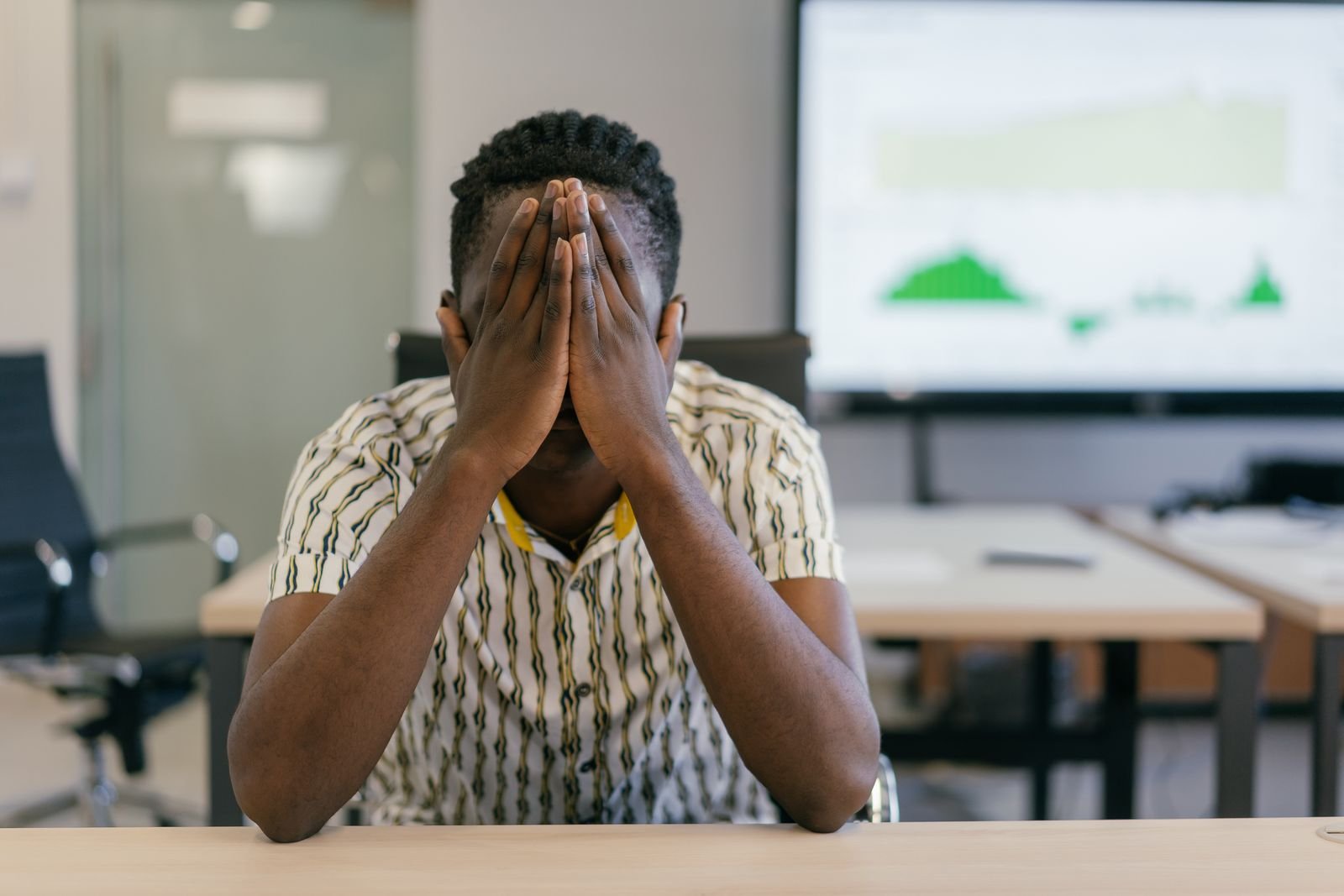 Man sitting at a desk with his head in his hands