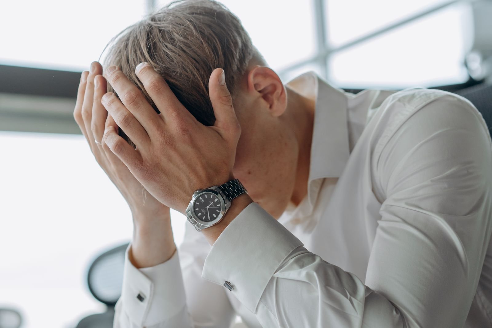 Man sitting with his hands pressed to his head