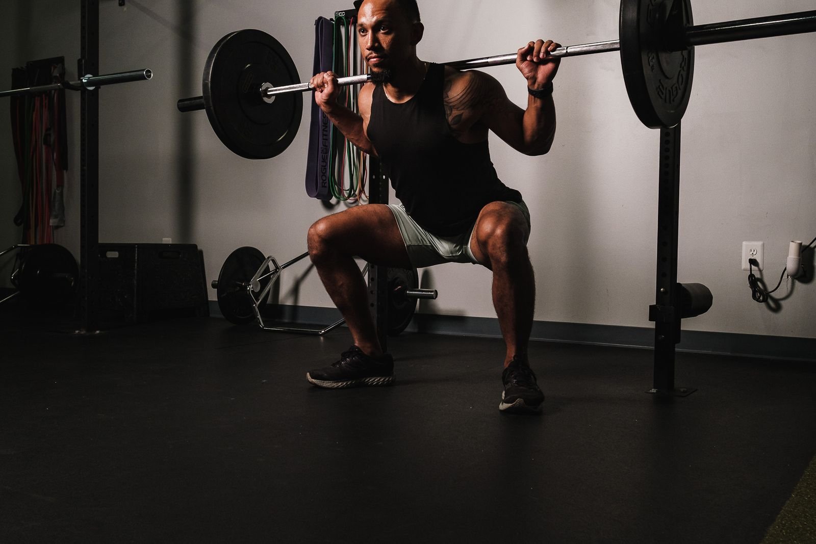 Man squatting with a barbell in a power rack