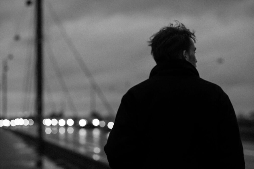 Man walking across a bridge at night, black and white