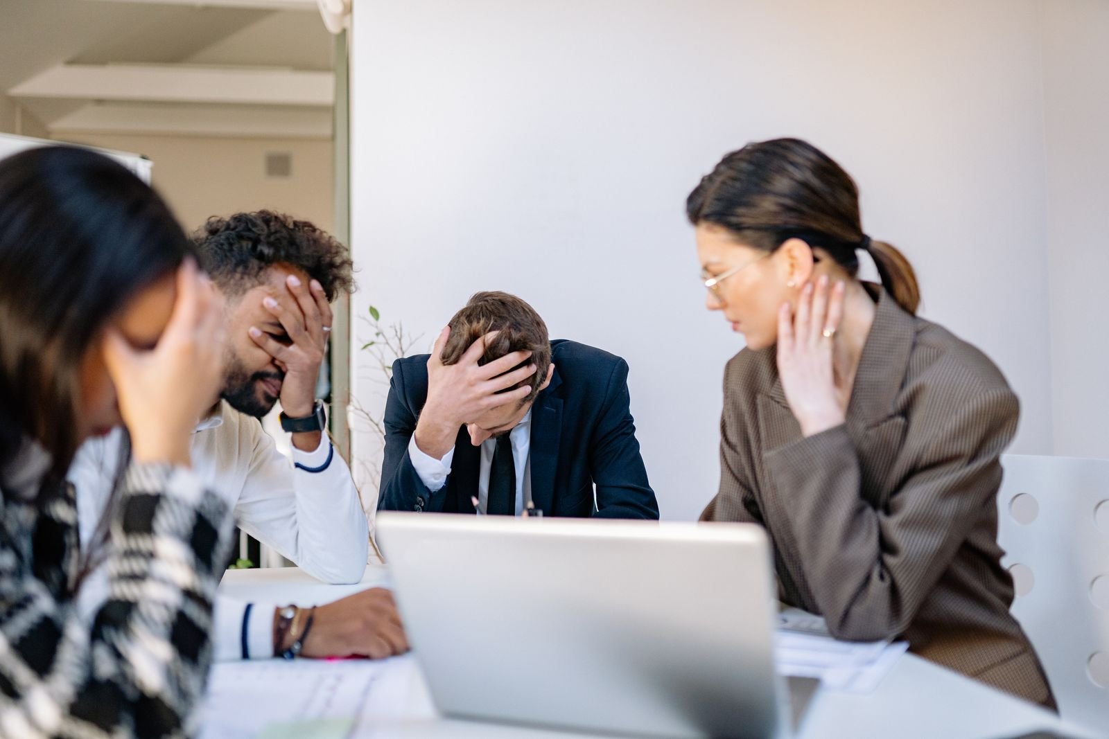 Man with his head in his hands during a work meeting